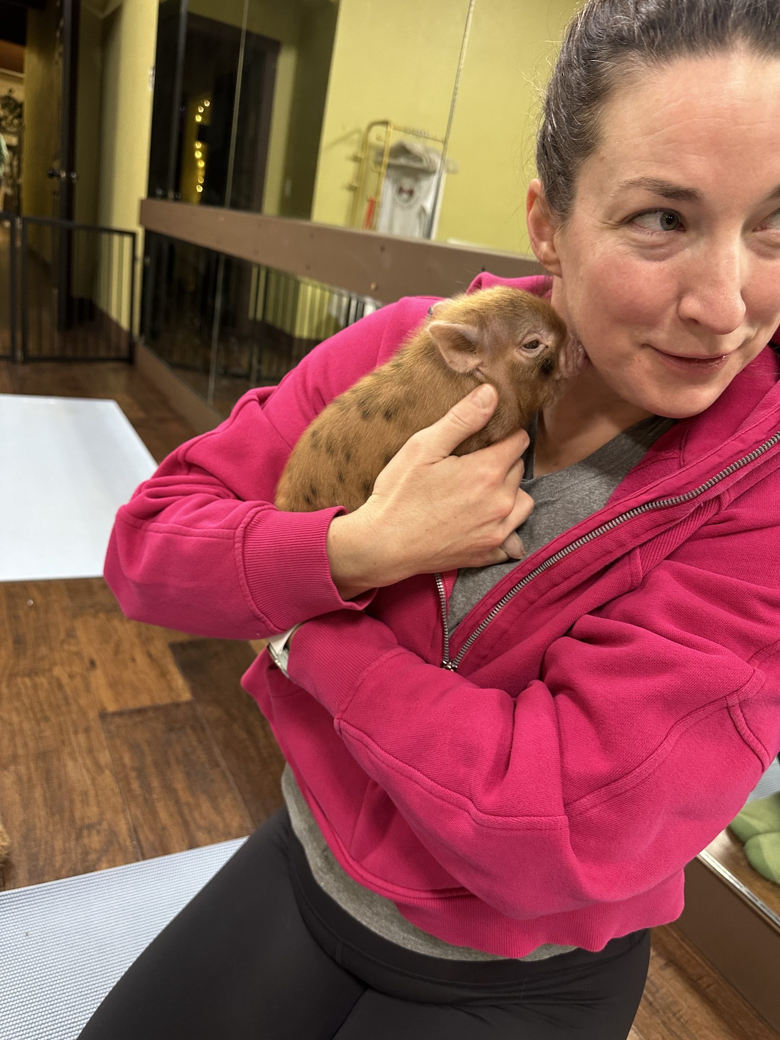 A guest holding a piglet close during a special Paws & Pose session